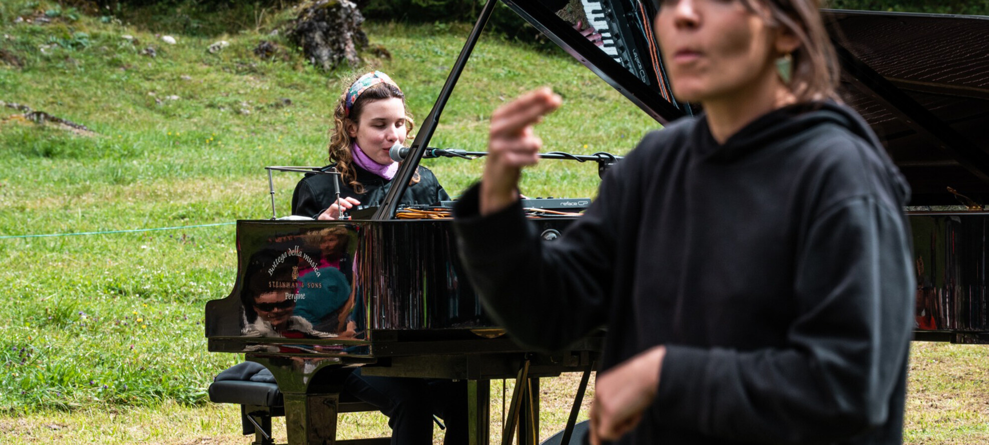 Während der Künstler mit Klavierbegleitung singt, übersetzt der Gebärdensprachen-Dolmetscher den Text des Liedes in Gebärdensprache.