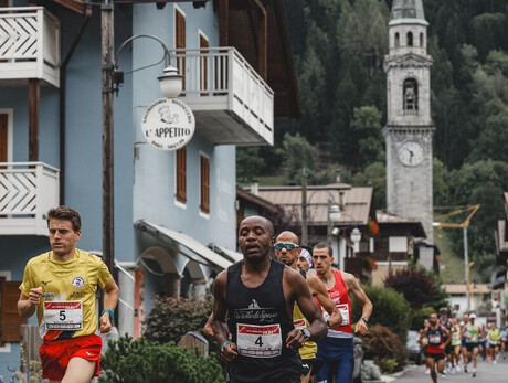 Group of runners racing through a mountain village with a church in the background.