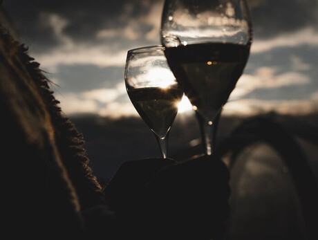 Two wine glasses at sunset with cloudy sky in the background