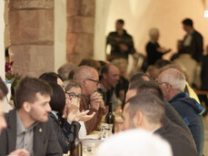 Long banquet tables under the portico of the cloister of the former Augustinian convent, filled with joyful people enjoying dinner and the company of friends.