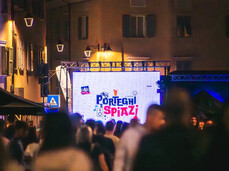 Persone che festeggiano in paese davanti a un maxischermo