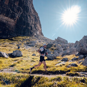 The image shows an athlete from the Dolomiti di Brenta Trail with the Dolomites in the background