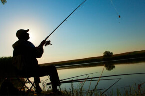 a fisherman ready to cast his float with his fishing rod at dawn