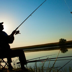 a fisherman ready to cast his float with his fishing rod at dawn