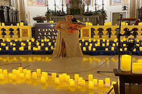 A WELL-DRESSED WOMAN AMIDST MANY CANDLES INSIDE A CHURCH