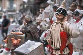 Nell'immagine si vede una strada di Napoli dove vendono statutte di pulcinella e cornetti di peperoncino