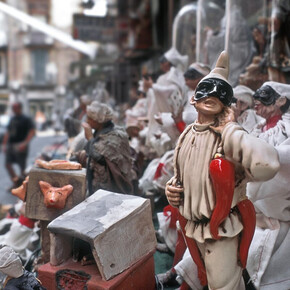 Nell'immagine si vede una strada di Napoli dove vendono statutte di pulcinella e cornetti di peperoncino