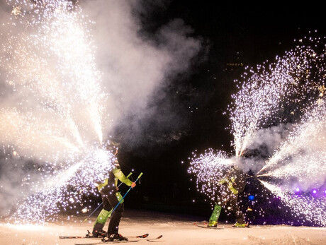 Un fermoimmagine dello spettacolo Ski Night Show mentre due sciatori scendono dalla pista con dei fuochi d'artificio molto scenici