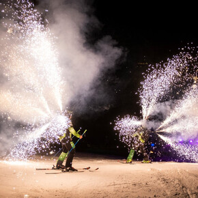 Un fermoimmagine dello spettacolo Ski Night Show mentre due sciatori scendono dalla pista con dei fuochi d'artificio molto scenici