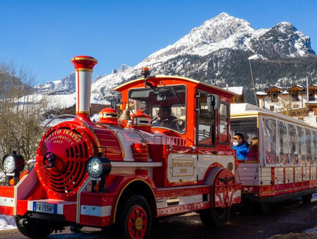 The tourist train goes round the old farms of Andalo. In the background, the whitewashed Piz Galin.