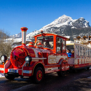 The tourist train goes round the old farms of Andalo. In the background, the whitewashed Piz Galin.