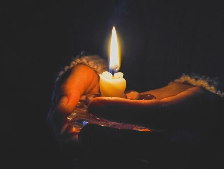 Santa Lucia arrives in Andalo A hand holds a string of lights, with a dark background and blurred points of light creating a magical and evocative atmosphere