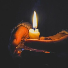 A hand holds a string of lights, with a dark background and blurred points of light creating a magical and evocative atmosphere
