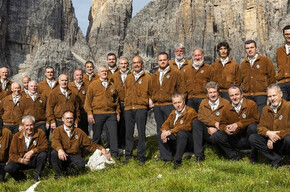 L'immagine mostra il coro Campanil Bas mentre canta ai piedi dell'omonima cima tra le Dolomiti di Brenta