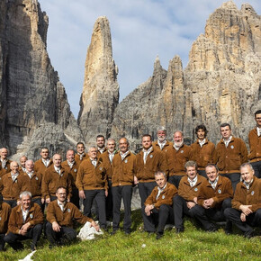L'immagine mostra il coro Campanil Bas mentre canta ai piedi dell'omonima cima tra le Dolomiti di Brenta