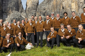 Nell'immagine si vede il Coro Campanil Bas con lo sfondo delle montagne di Molveno.