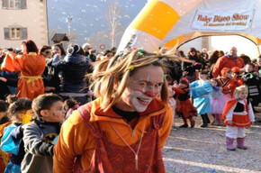 EIN SYMPATHISCHER CLOWN, DER MIT DEN KINDERN AUF DEM PLATZ MIT KONFETTI UND STERNENSPIRALEN SPIELT