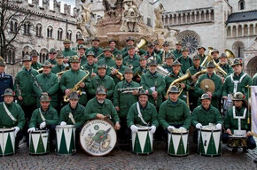 L'immagine mostra i componenti della Fanfara sezione ANA di Trento in posa sotto la fontana del Nettuno, in piazza Duomo a Trento