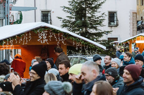 Piazza piena di persone che festeggiano durante le feste natalizie con concerti e casette di prodotti tipici