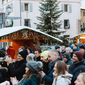 Piazza piena di persone che festeggiano durante le feste natalizie con concerti e casette di prodotti tipici