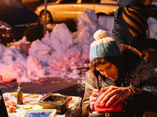 La foto ritrae un artista pitturare il viso ad un bambino per l'occasione natalizia