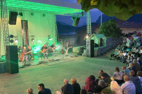 Image of the band playing and singing in the church square in Molveno in front of the listening crowd 