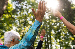 Foto di persone che alzano le mani al cielo in un bosco